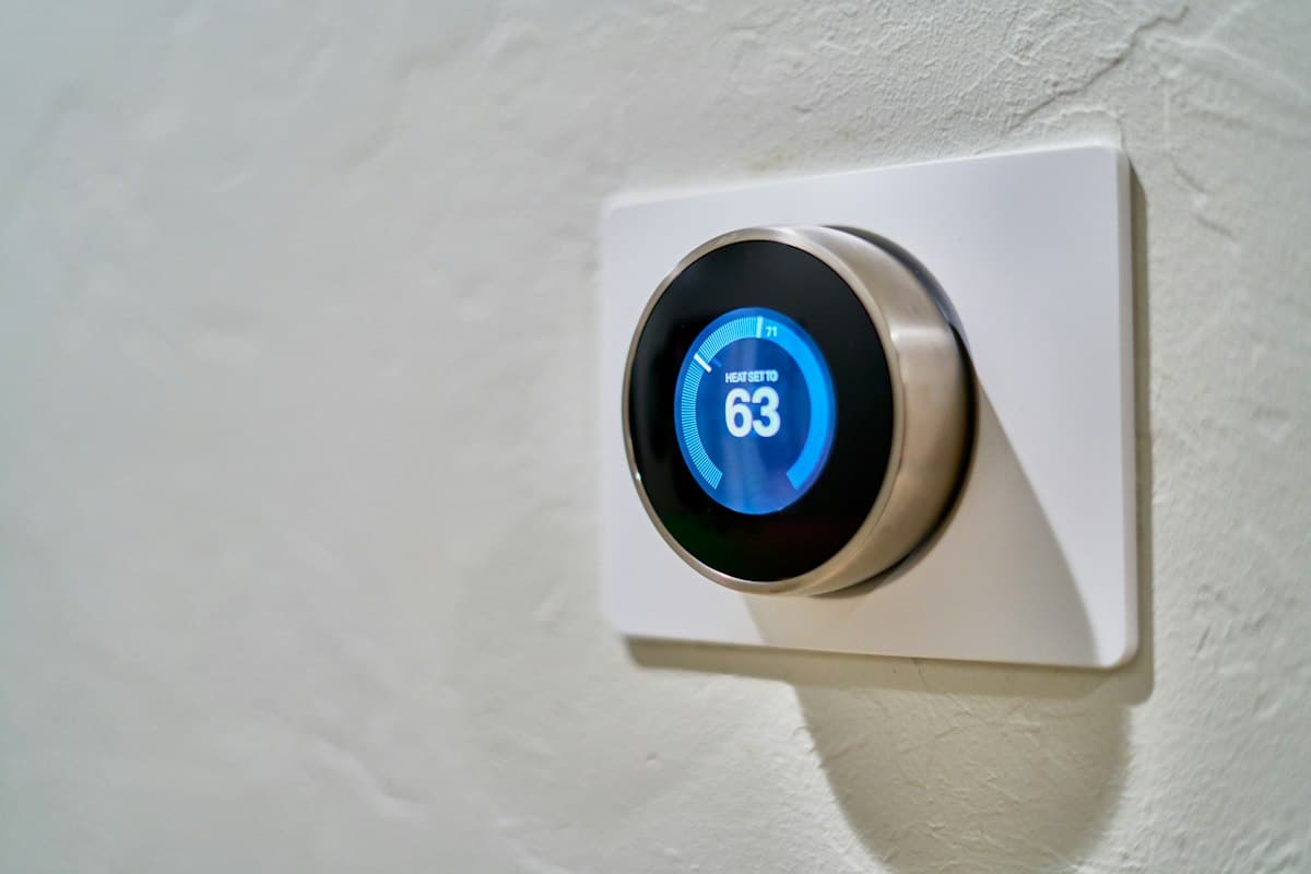 A smart thermostat on a wall, its display set to a specific temperature